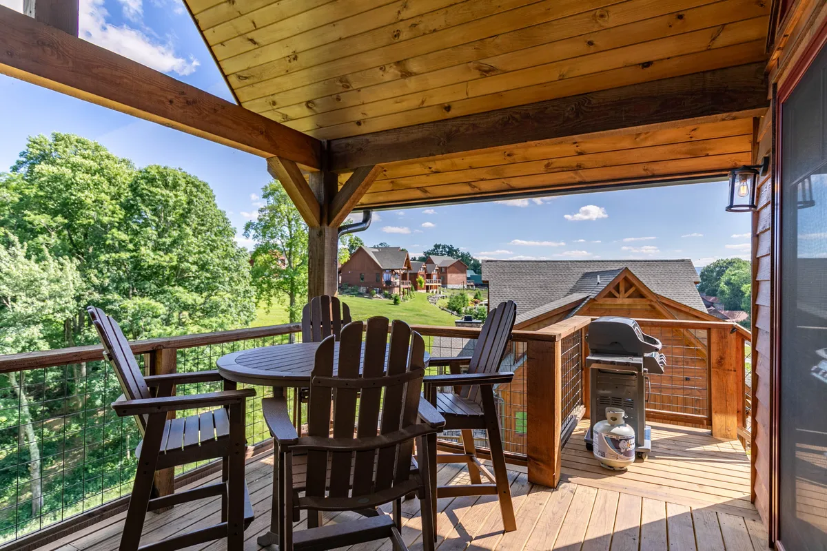 The image displays a wooden deck with outdoor seating, a grill, and lush greenery beyond. The setting is ideal for barbecues, outdoor dining, and relaxing in the fresh air, bringing families together for meals and social time surrounded by nature.