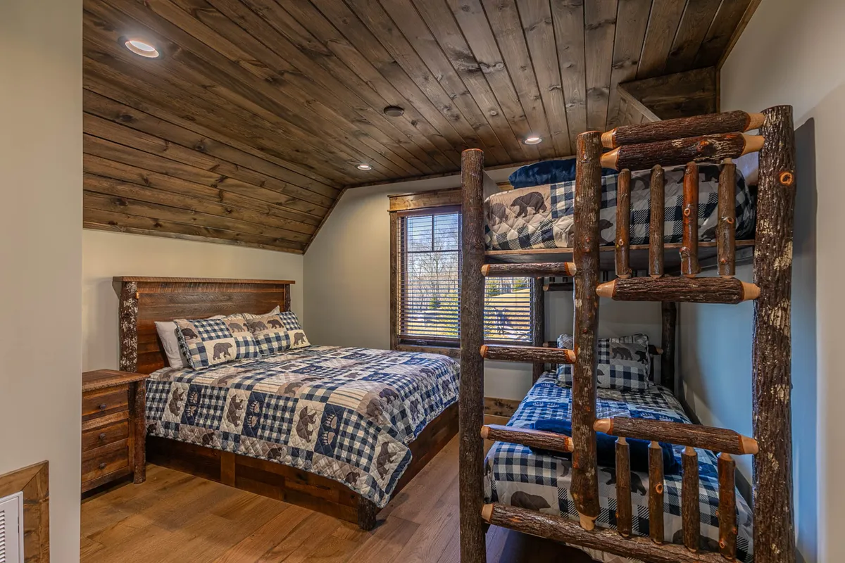 The photo features an inviting bedroom with a queen bed and a twin-over-twin bunk bed, complemented by wooden furniture and textural patterns. The arrangement is practical for families or groups, providing both flexibility and comfort in the sleeping quarters.